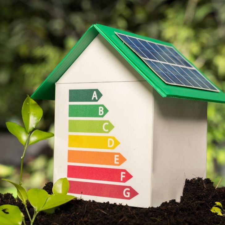 Casa em miniatura com classificacao de eficiencia energetica e painel solar no telhado